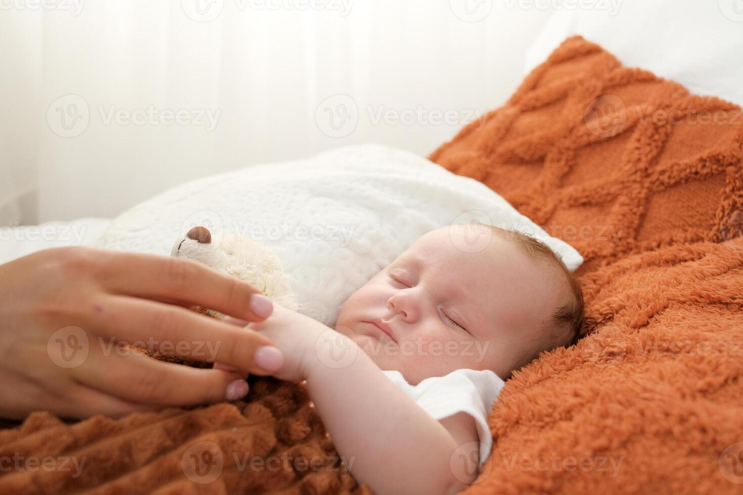un recién nacido bebé duerme en un cama. un osito de peluche oso mentiras cercano. madre y niño. foto