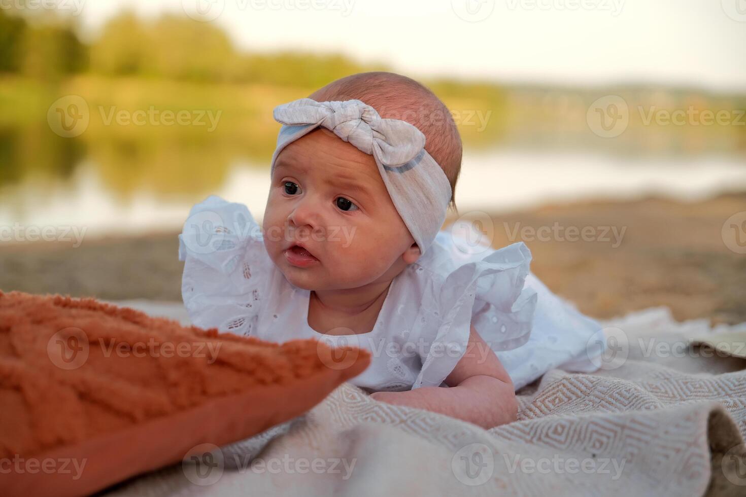 newborn baby girl lies on the beach. in a white dress. photo