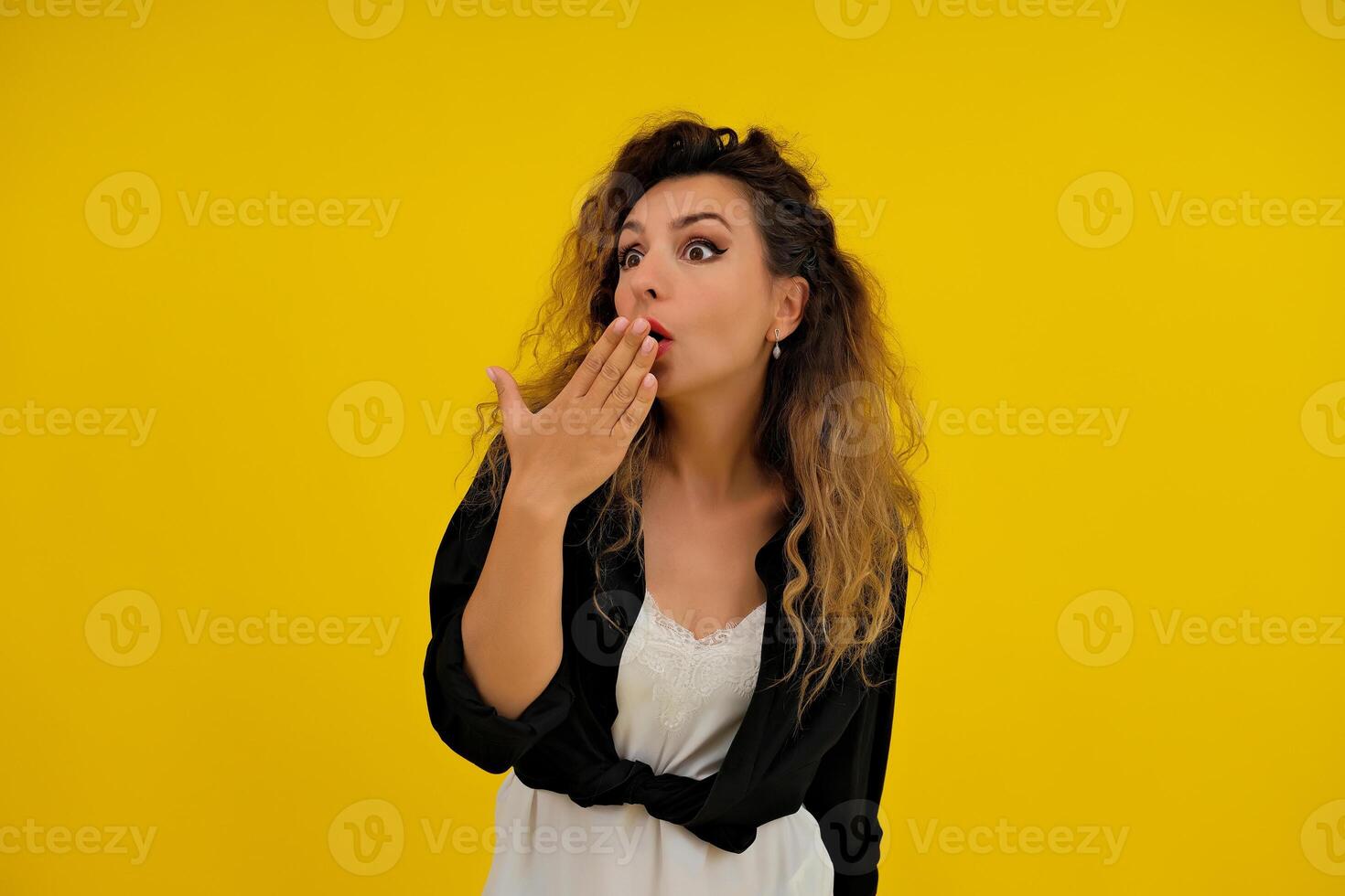 Close-up portrait of a beautiful girl on a yellow background. woman shows surprise. Shocked surprised stunned. positive human emotions photo