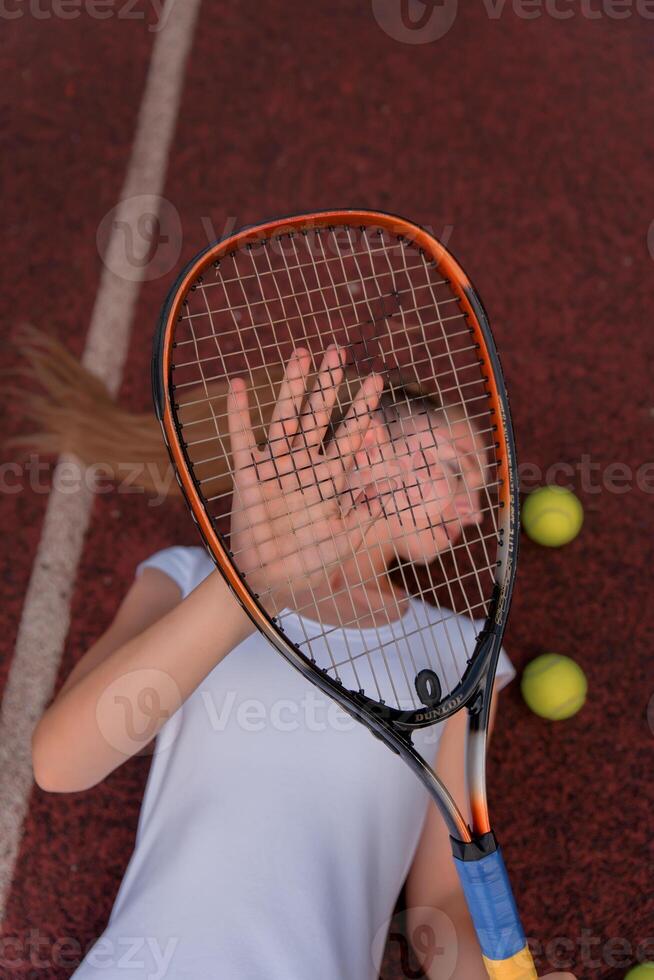 a girl in a white sports dress stands on a tennis court and holds a racket. portrait of a girl on the tennis court. photo