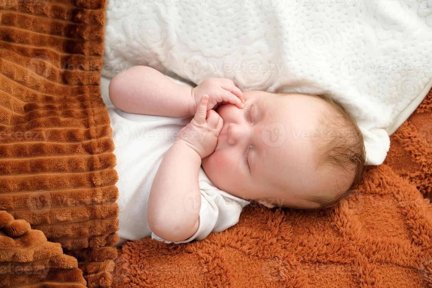 a newborn baby sleeps on a bed. A teddy bear lies nearby. mother and child. photo
