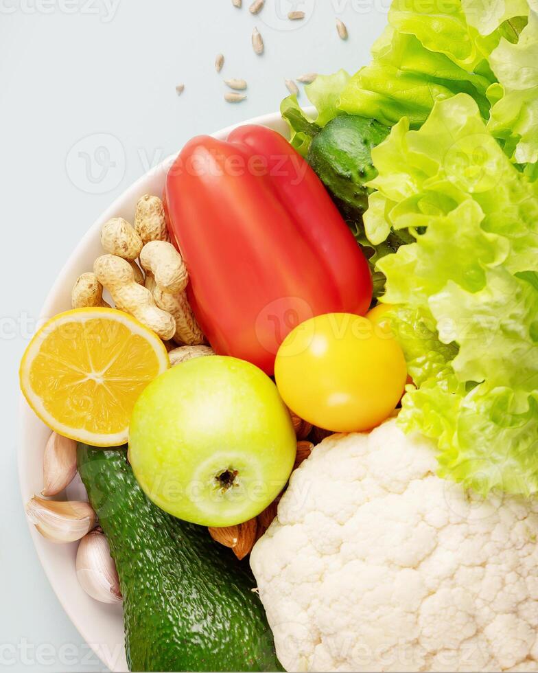 Organic vegetables and fruits, nuts, seeds on a white plate photo