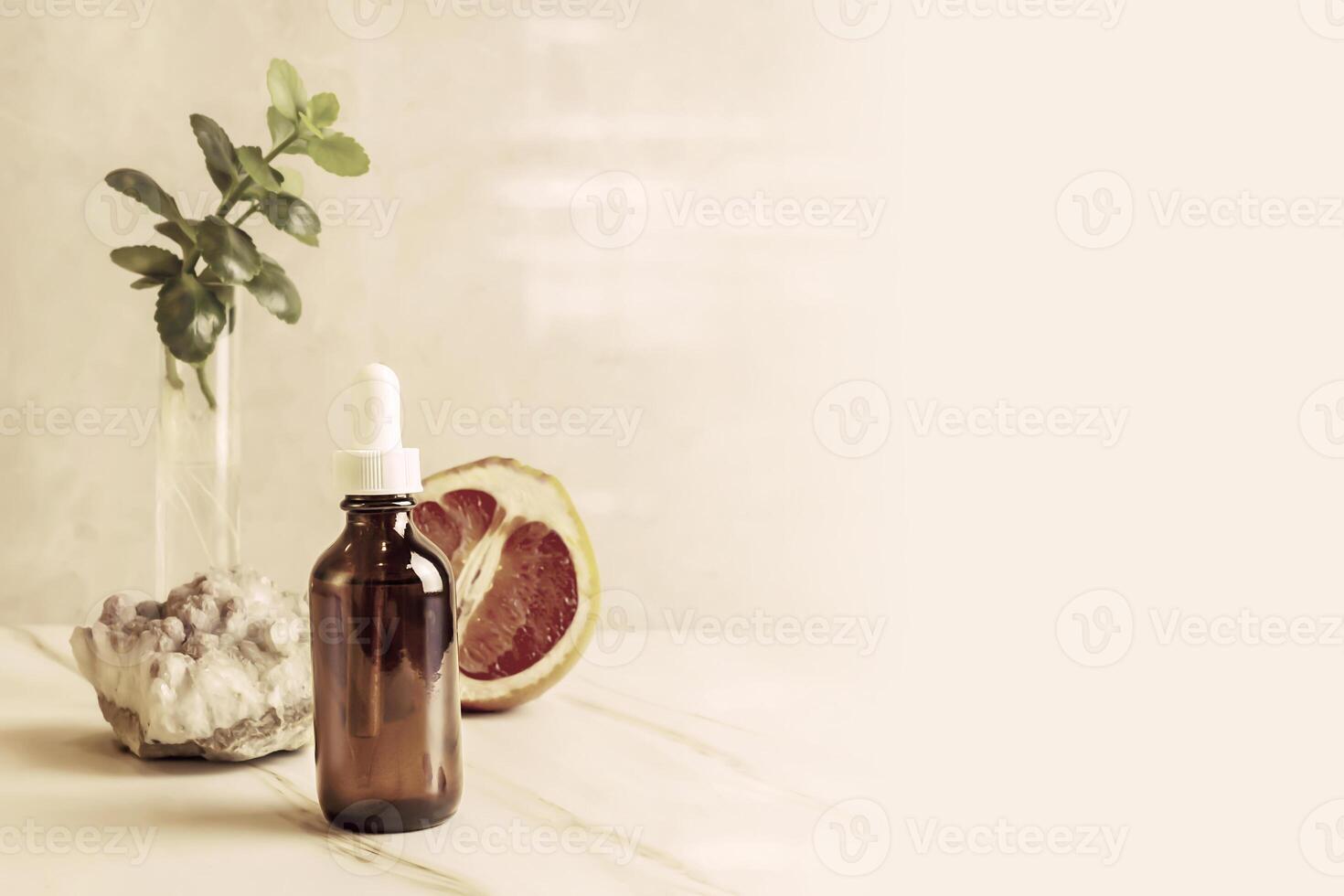 Citrus essential oil, grapefruit, mineral stone and green branch on a marble background photo