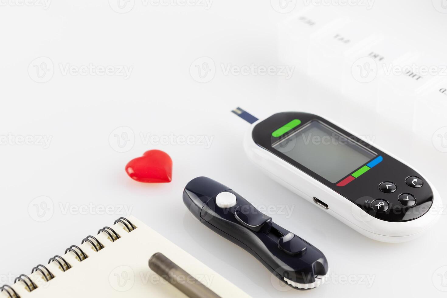 Glucose meter, lancets, pills and diary of control with pen photo