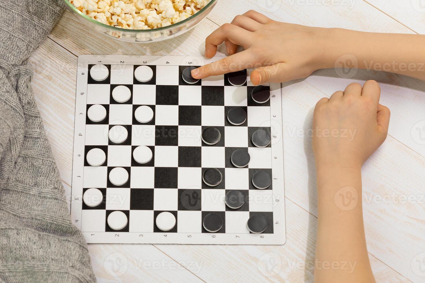 A chess board with checkers and a child's hand making a move photo