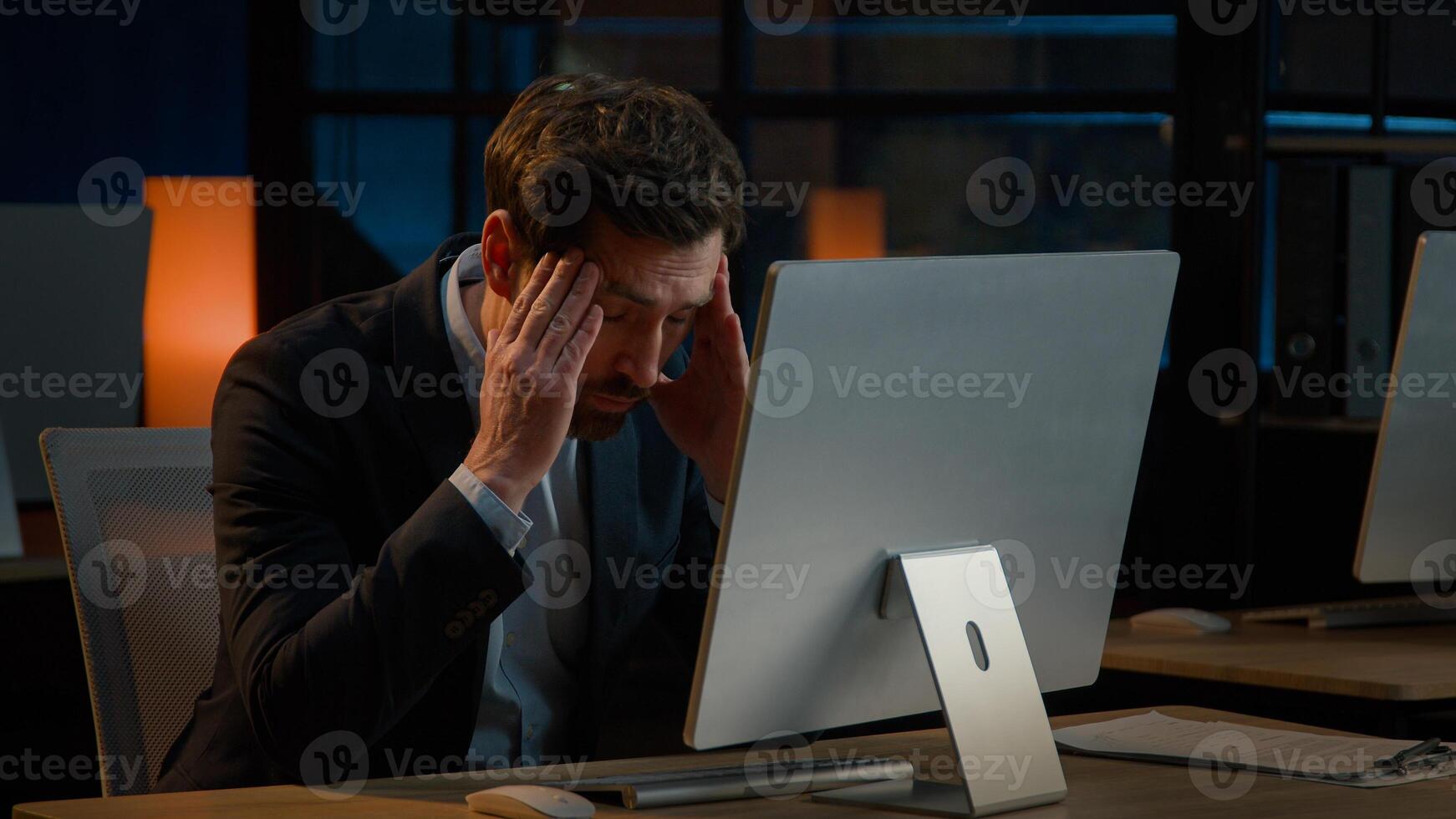 Exhausted Caucasian businessman adult man work overtime in office late night tired entrepreneur worried business problem make mistake failure difficulties with computer read bad news headache stress photo