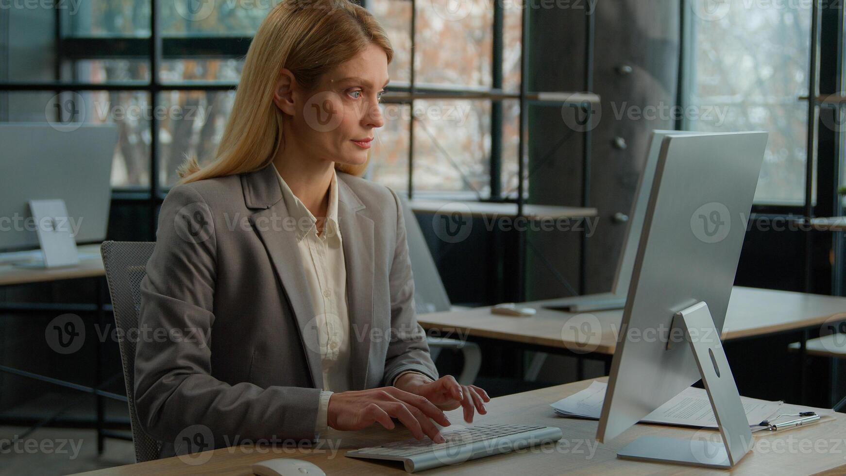 Female Caucasian adult freelancer lady employee businesswoman middle-aged woman secretary using modern wireless tech usage app. Office worker at desk texting on computer internet work online working photo