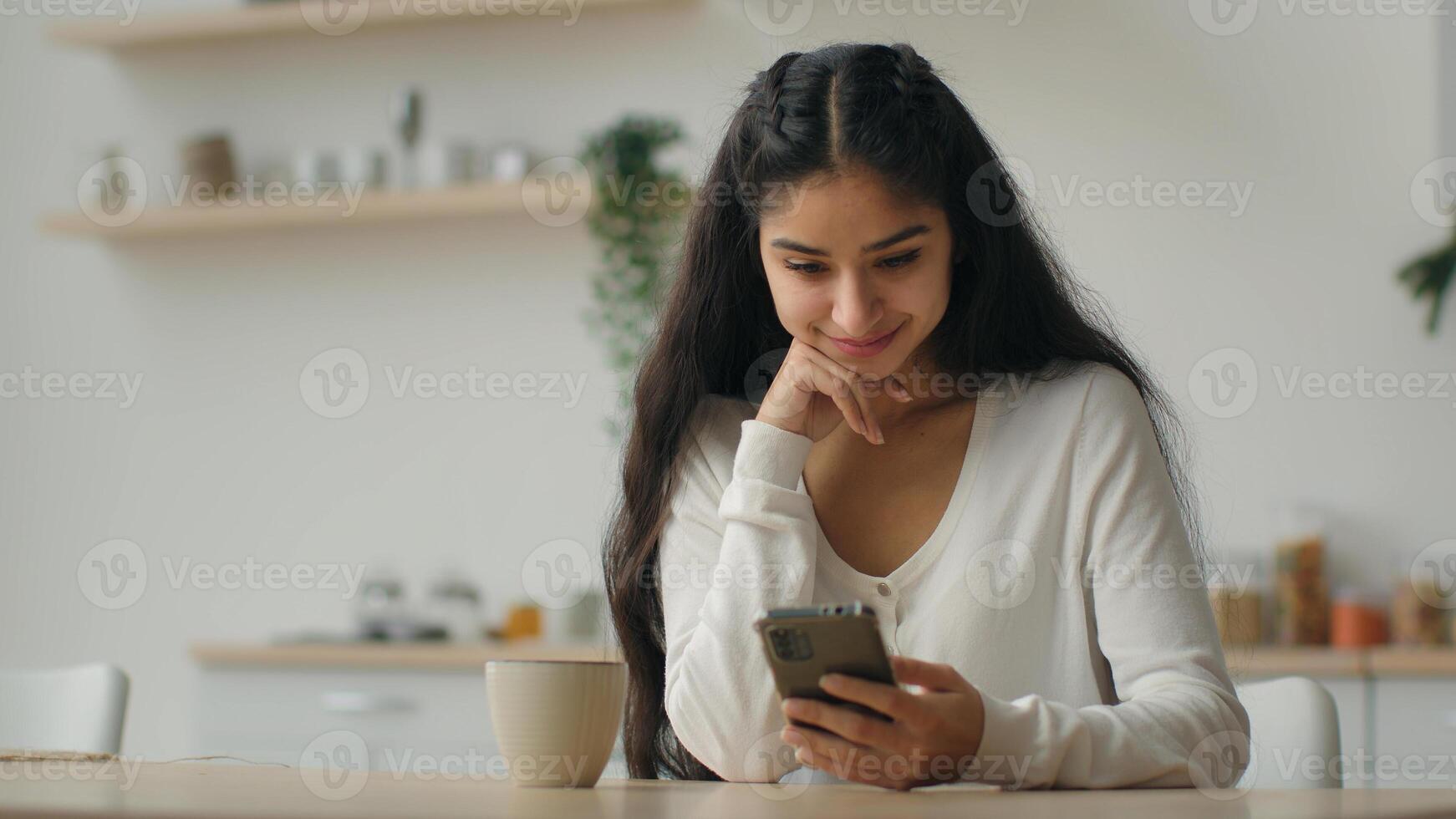 Millennial smartphone user arabian woman typing message in domestic kitchen female homeowner girl using cellphone online app make order food delivery service on mobile phone browsing cooking website photo