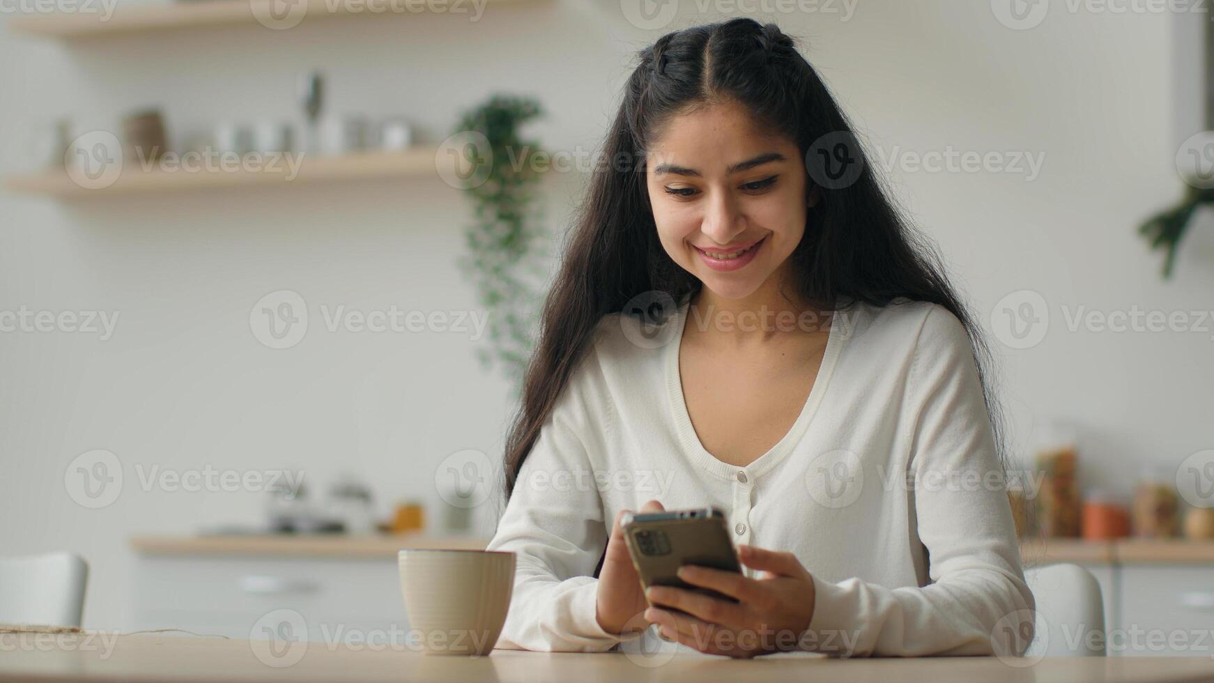 Millennial smartphone user arabian woman typing message in domestic kitchen female homeowner girl using cellphone online app make order food delivery service on mobile phone browsing cooking website photo