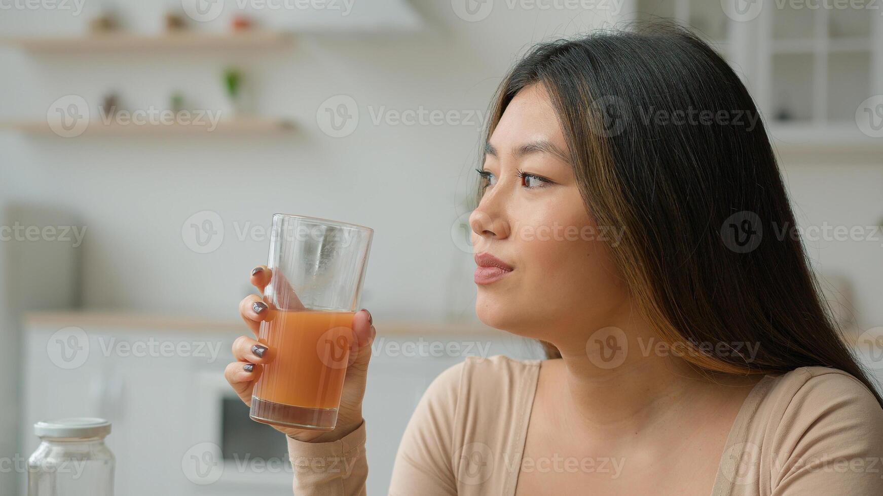 Korean woman drinking fresh smoothie orange juice. Asian vegetarian girl tasting glass of vitamin fruity cocktail peach drink healthy diet weight loss healthcare nourishment morning detox in kitchen photo