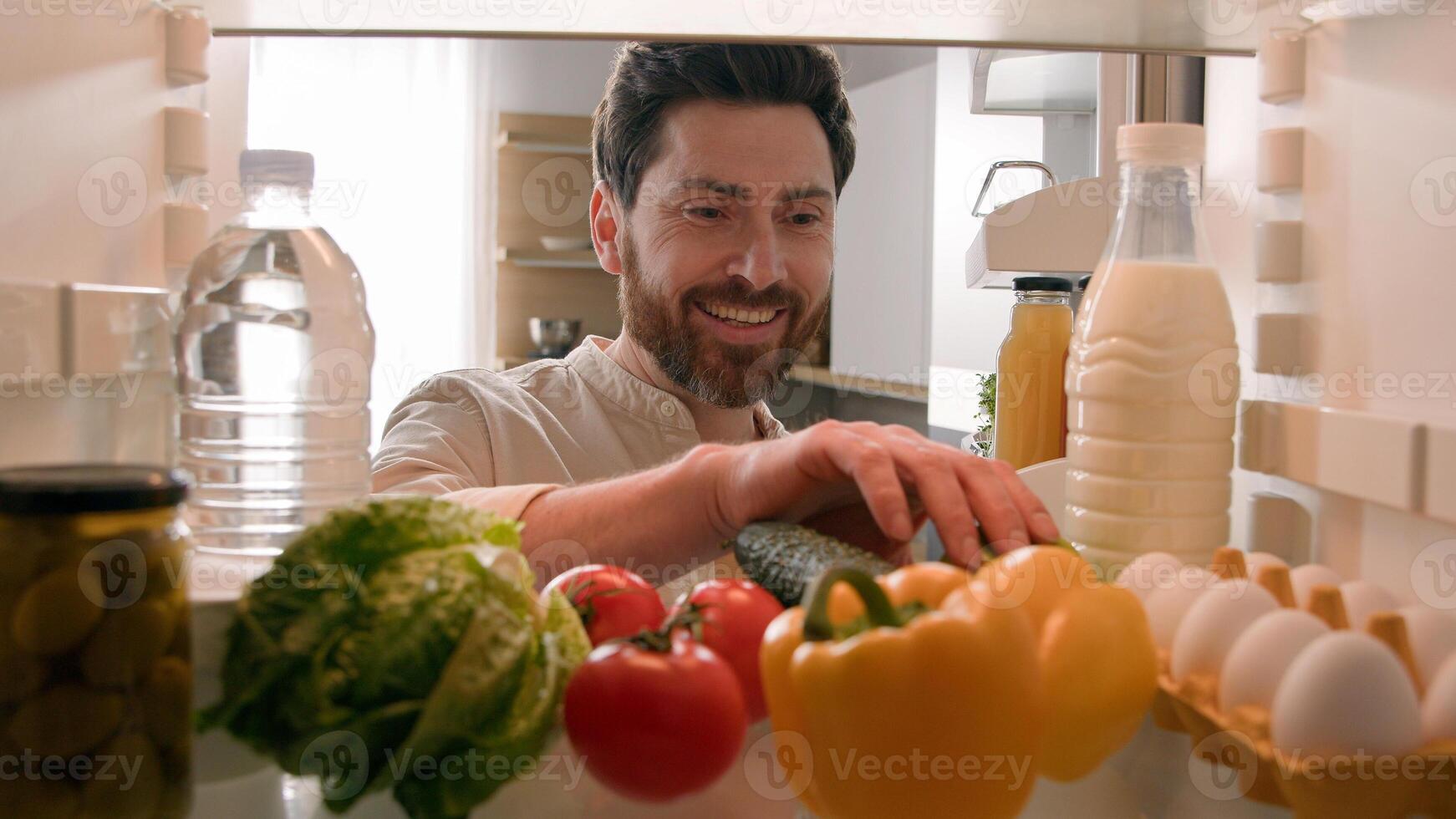 Point of view POV inside refrigerator hungry Caucasian man guy male chef open fridge with healthy vegetables choosing searching take eat apple eating fruit at home kitchen food delivery health diet photo