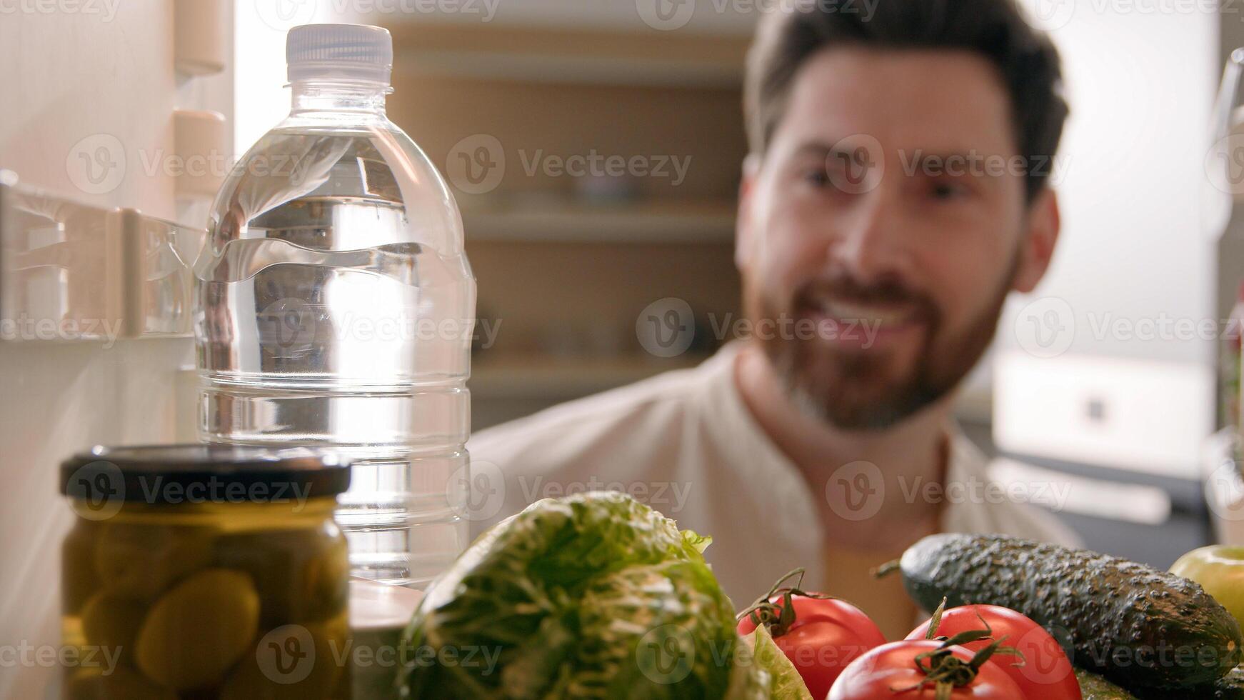 Point of view POV inside refrigerator Caucasian man male thirsty guy open fridge full of products many vegetables at home kitchen take out bottle with cold still fresh water hydrated food delivery photo