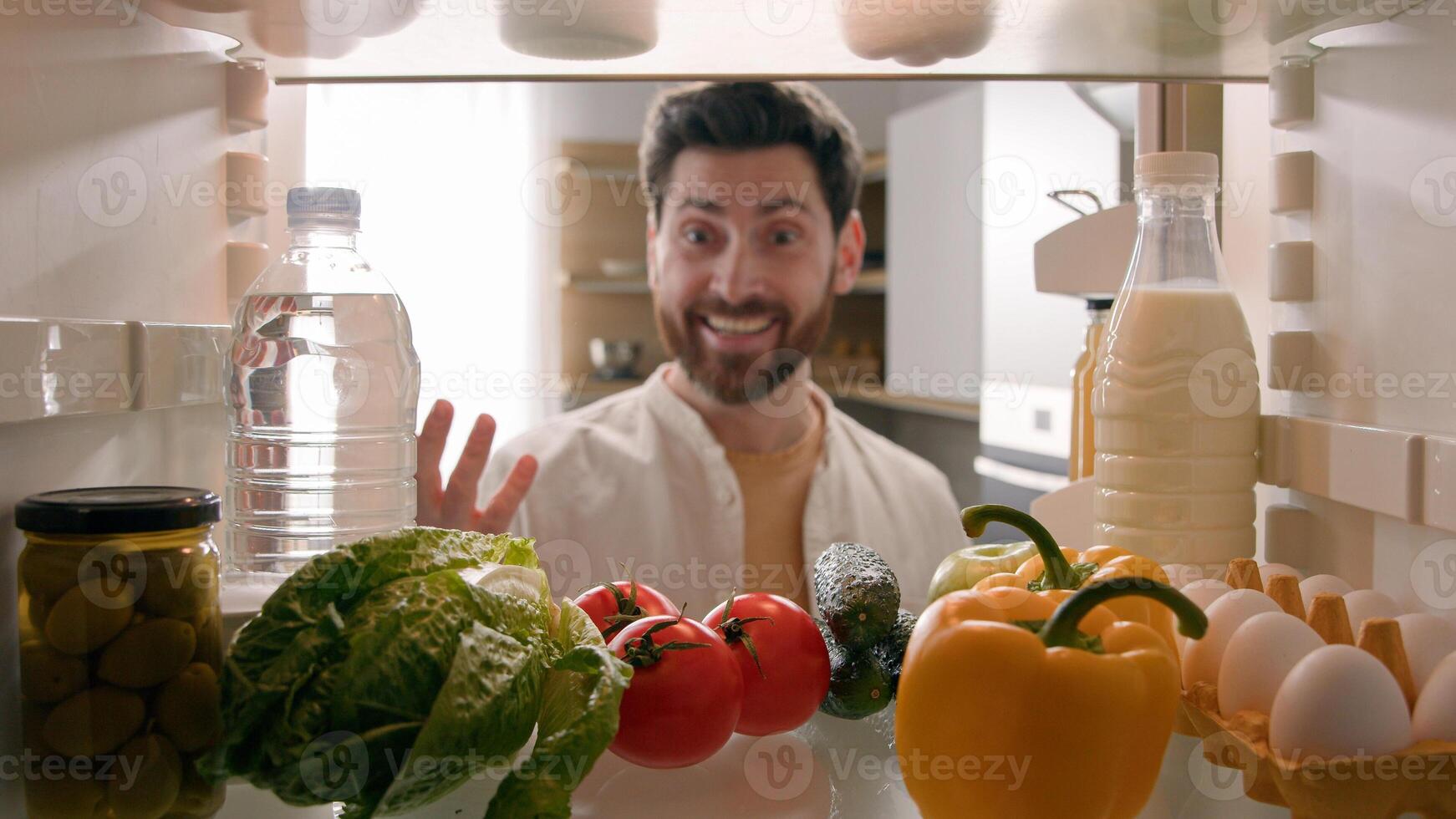 Point of view POV inside refrigerator happy excited hungry Caucasian man open fridge full of healthy vegetables many products meal take sniffing fresh tomato good smell food delivery service cooking photo