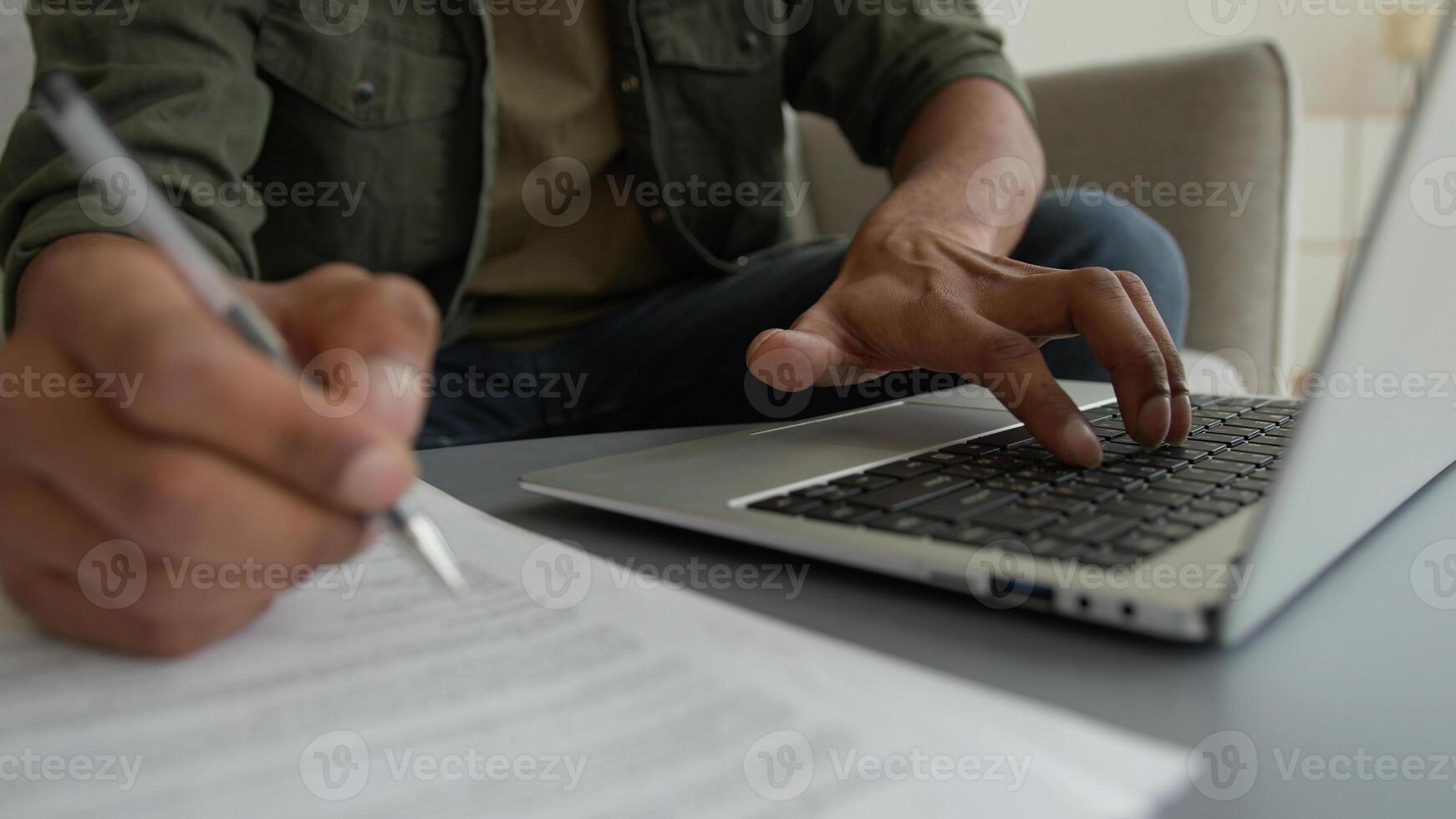 Close up view unrecognizable man male guy working laptop from home browsing internet cropped shot businessman typing computer write notes writing legal document business paperwork pay bills loan taxes photo