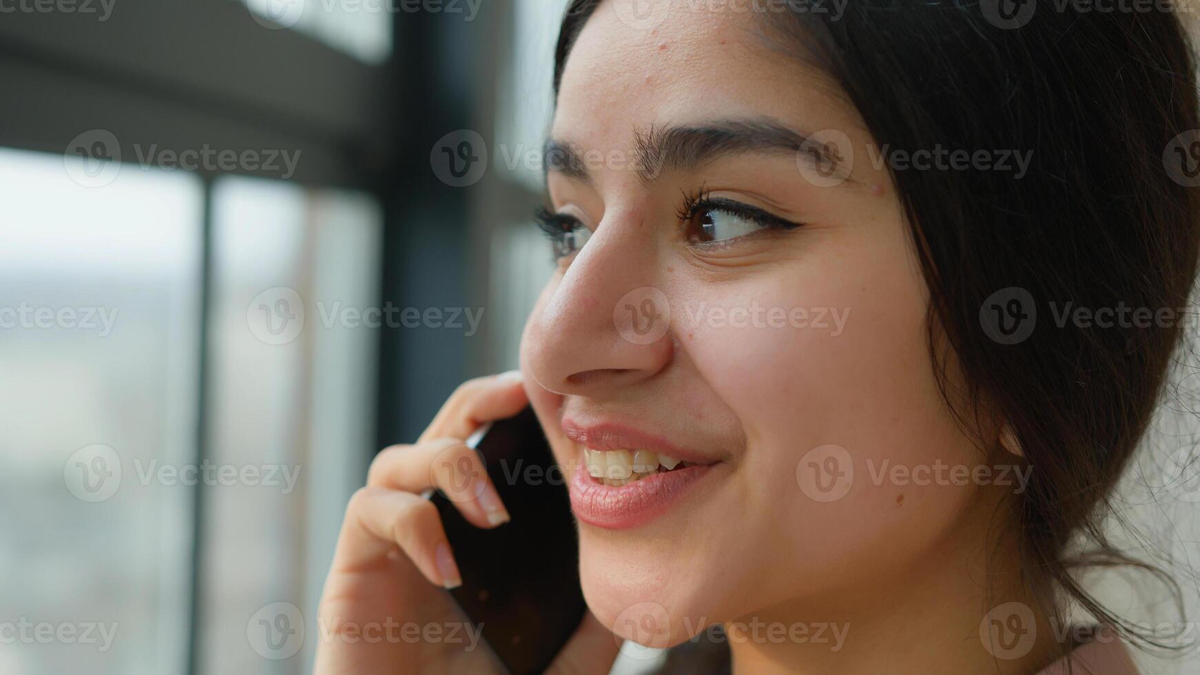 Close up head shot Arabian girl talking mobile phone near window smiling female businesswoman lady speak business call Indian woman at home office calling laughing talk smartphone distant conversation photo