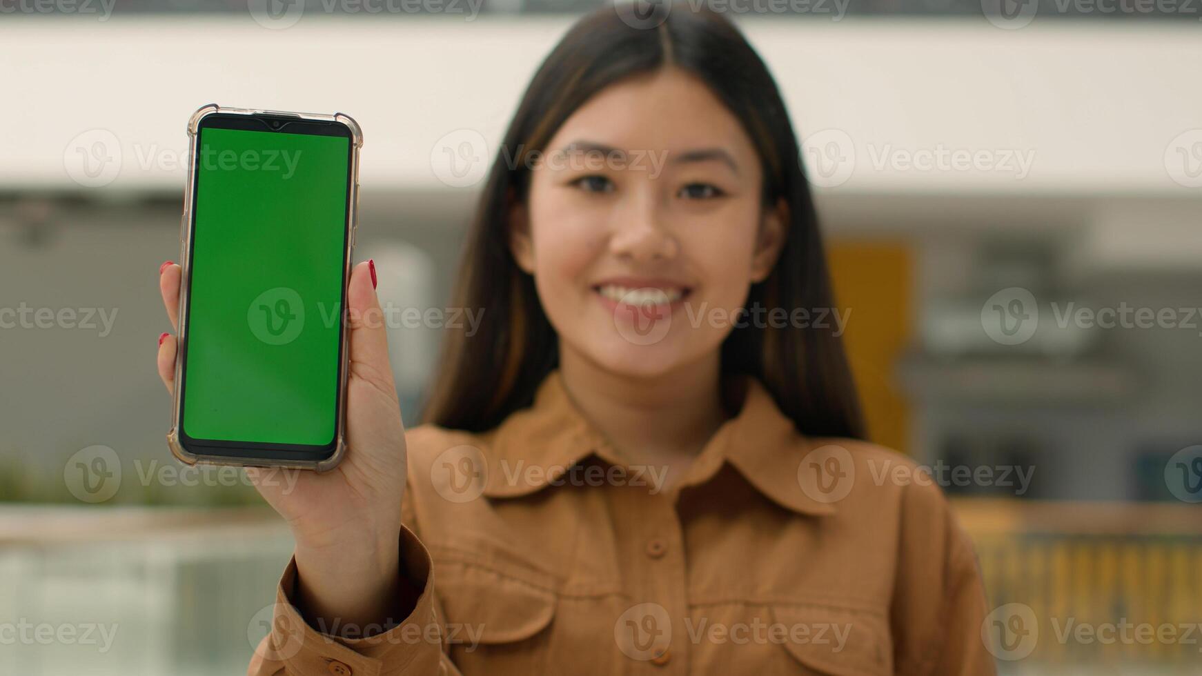 Mobile phone device focus blurred Asian business woman chinese girl hold smartphone green mock-up happy businesswoman advertise cellphone chroma key empty display web service cell gadget advertisement photo
