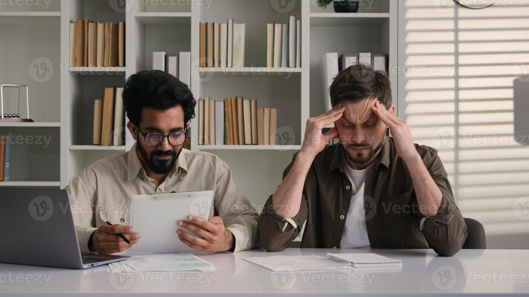 Overworked tired sick man suffer headache migraine health two multiracial colleagues discuss project with laptop multiethnic Arabian Indian Caucasian businessmen men solve teamwork problem in office photo
