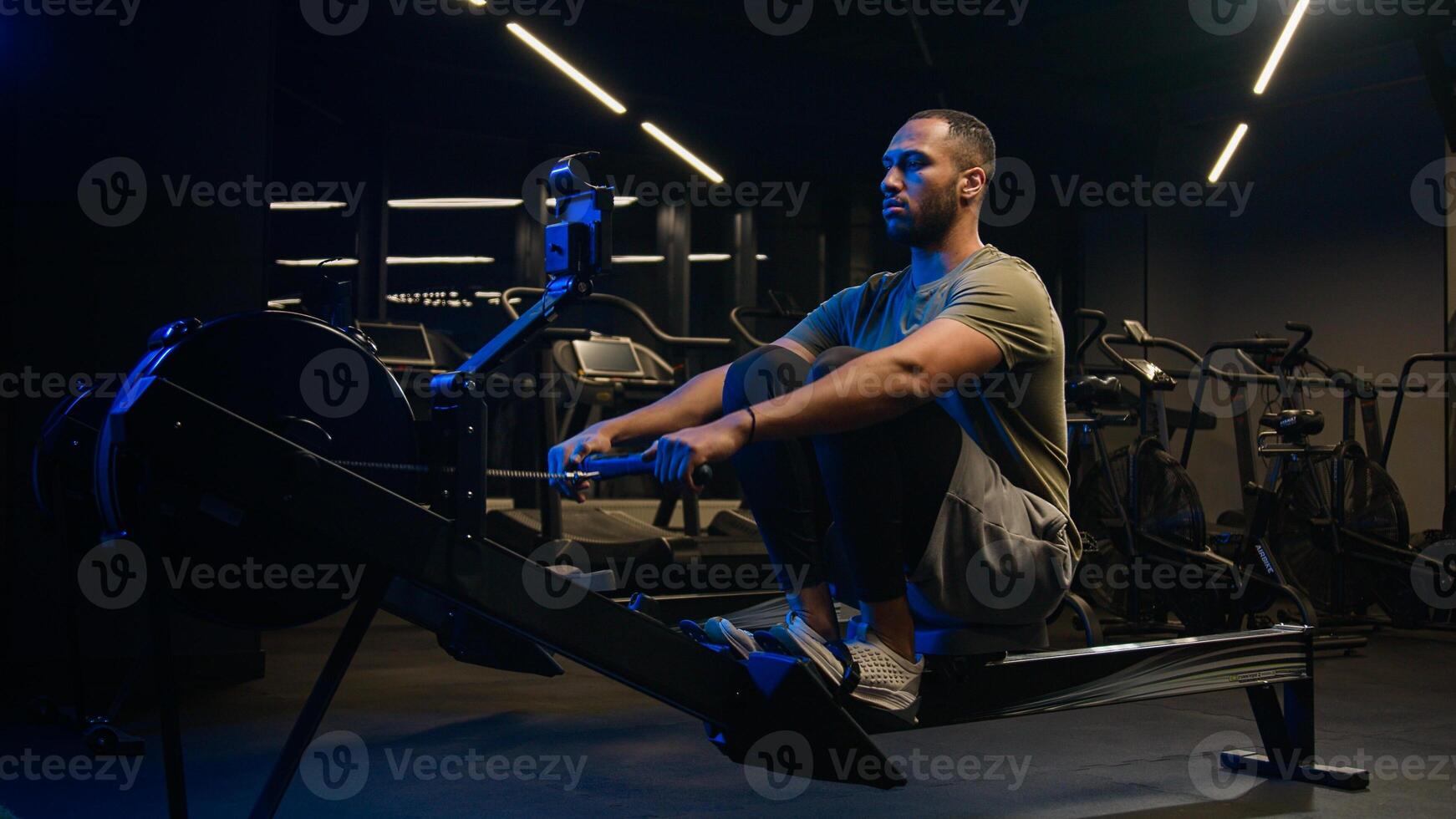 Sport hard weight exercise sporting bodybuilding workout gym pulling rowing machine sitting lift low row motivation healthy African American man sporty male guy athlete sportsman bodybuilder trainer photo
