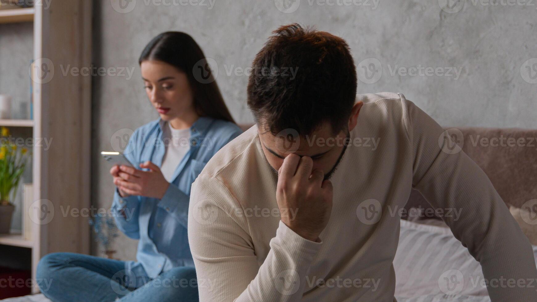 Caucasian couple problem relationship sad upset man sit separate from woman on bed offended on wife addicted gadget scrolling mobile phone smartphone ignoring husband internet social media addiction photo
