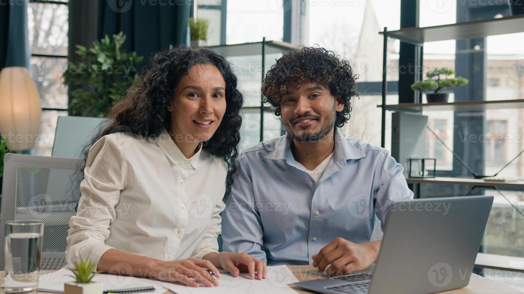 Multiethnic colleagues Arabian Latino man businessman Hispanic businesswoman woman discuss business project teamwork with laptop talk write report in office happy employees looking at camera smiling photo