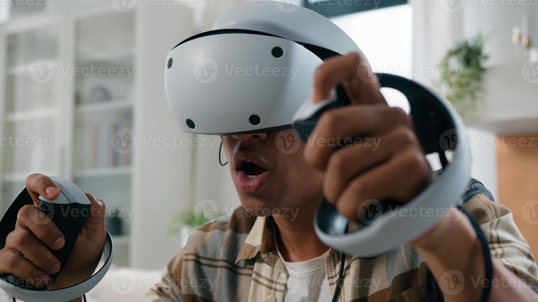 Excited happy African American man guy play virtual reality game at home holiday hobby modern technology gaming in VR helmet glasses cyberspace experience metaverse playing computer 3d world photo