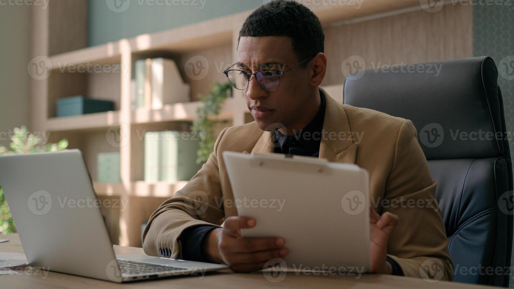 Business man African American accountant male office worker write financial data analysis plan strategy focused businessman work with laptop computer manage project study paper report signing document photo