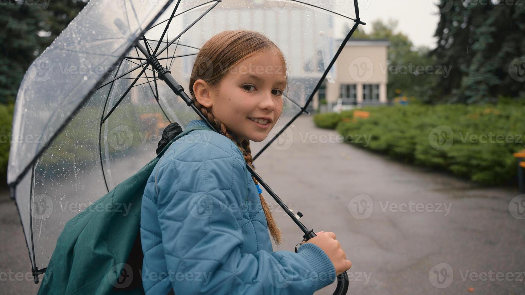 European happy little girl walking city street outside in rain with umbrella back views choolgirl going childhood charming child smile learner school park autumn weather weekend enjoying moving urban photo