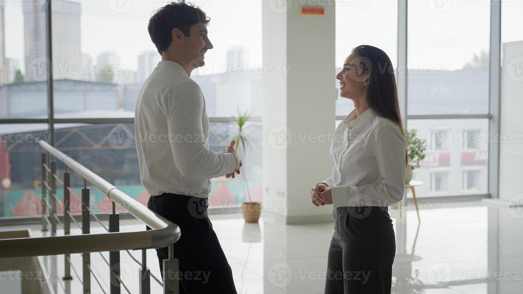 Businessman and businesswoman talking laughing in company hall corporate friendship business colleagues friends partners coworkers man woman talk friendly conversation in office lobby coworking break photo