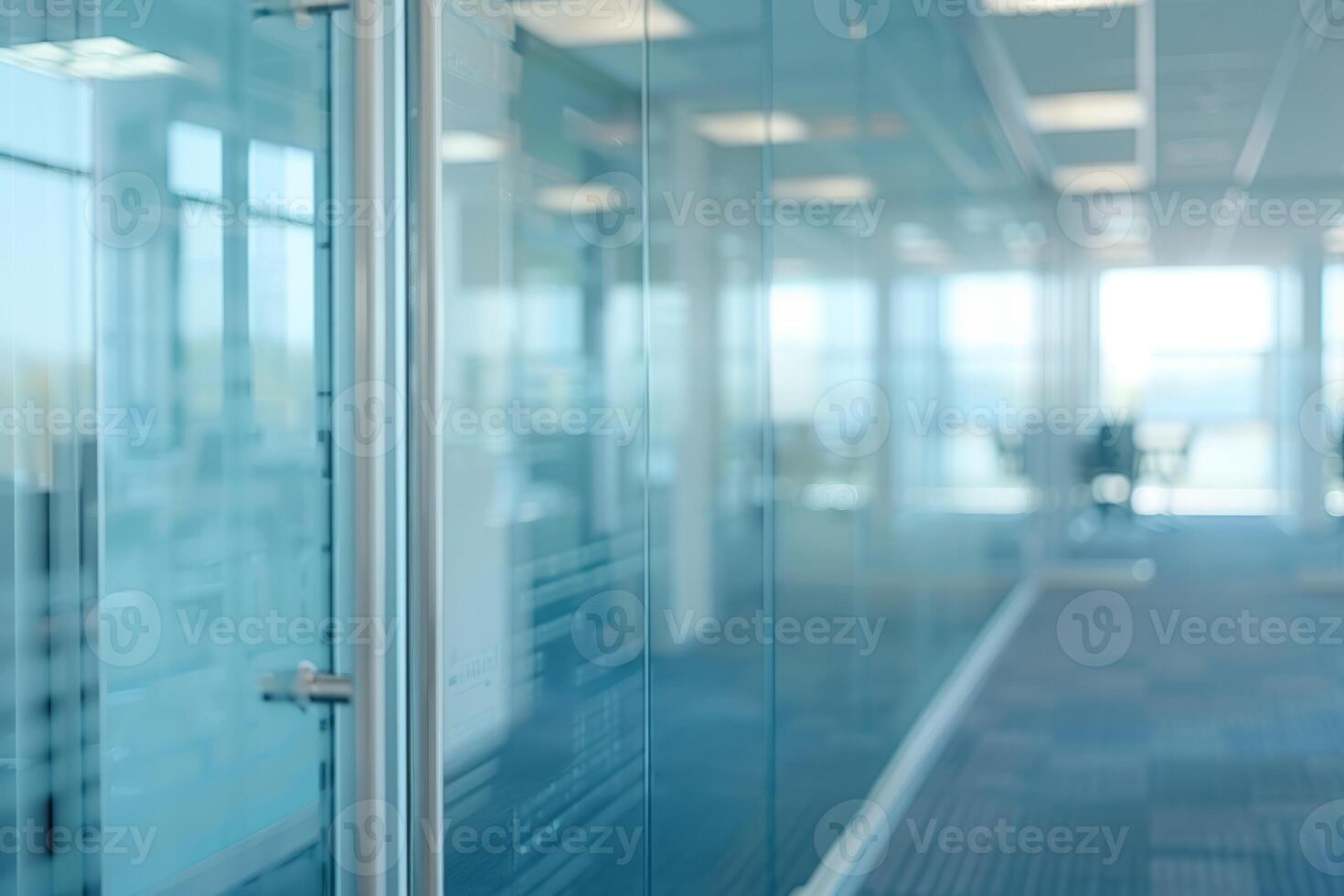 A large, empty office room with a sun shining through the windows. Modern space is made of glass and has a shiny, reflective surface photo