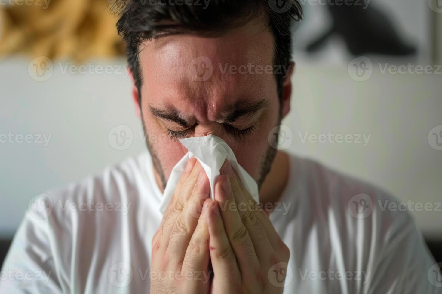 A handsome man is blowing his nose with a tissue during spring allergy season flowers blossom exhausted and uncomfortable allergens in air disease and sickness photo