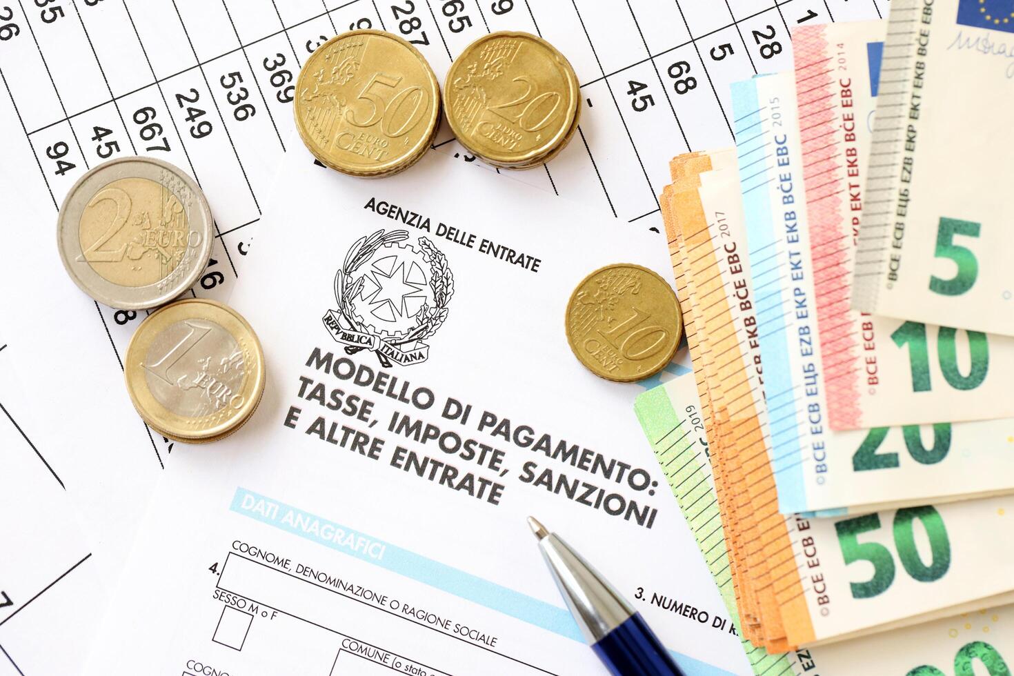 KYIV, UKRAINE - APRIL 20, 2024 Agenzia Delle Entrate logo from blank tax form and many euro banknotes on office table photo