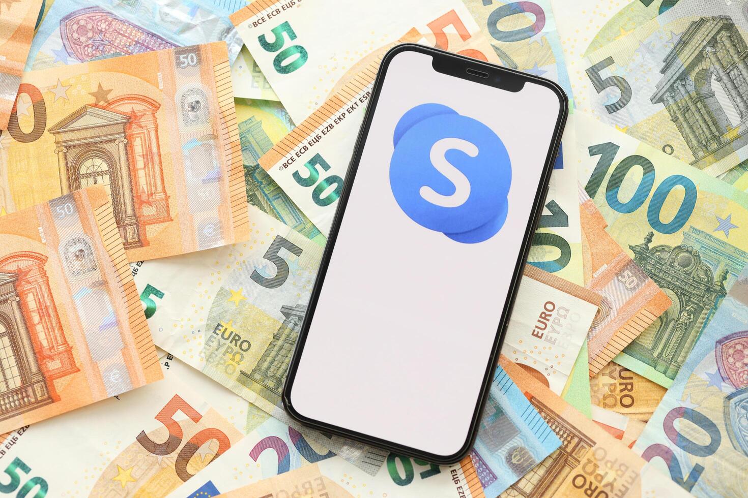 KYIV, UKRAINE - APRIL 1, 2024 Skype icon on smartphone screen on many euro money bills photo