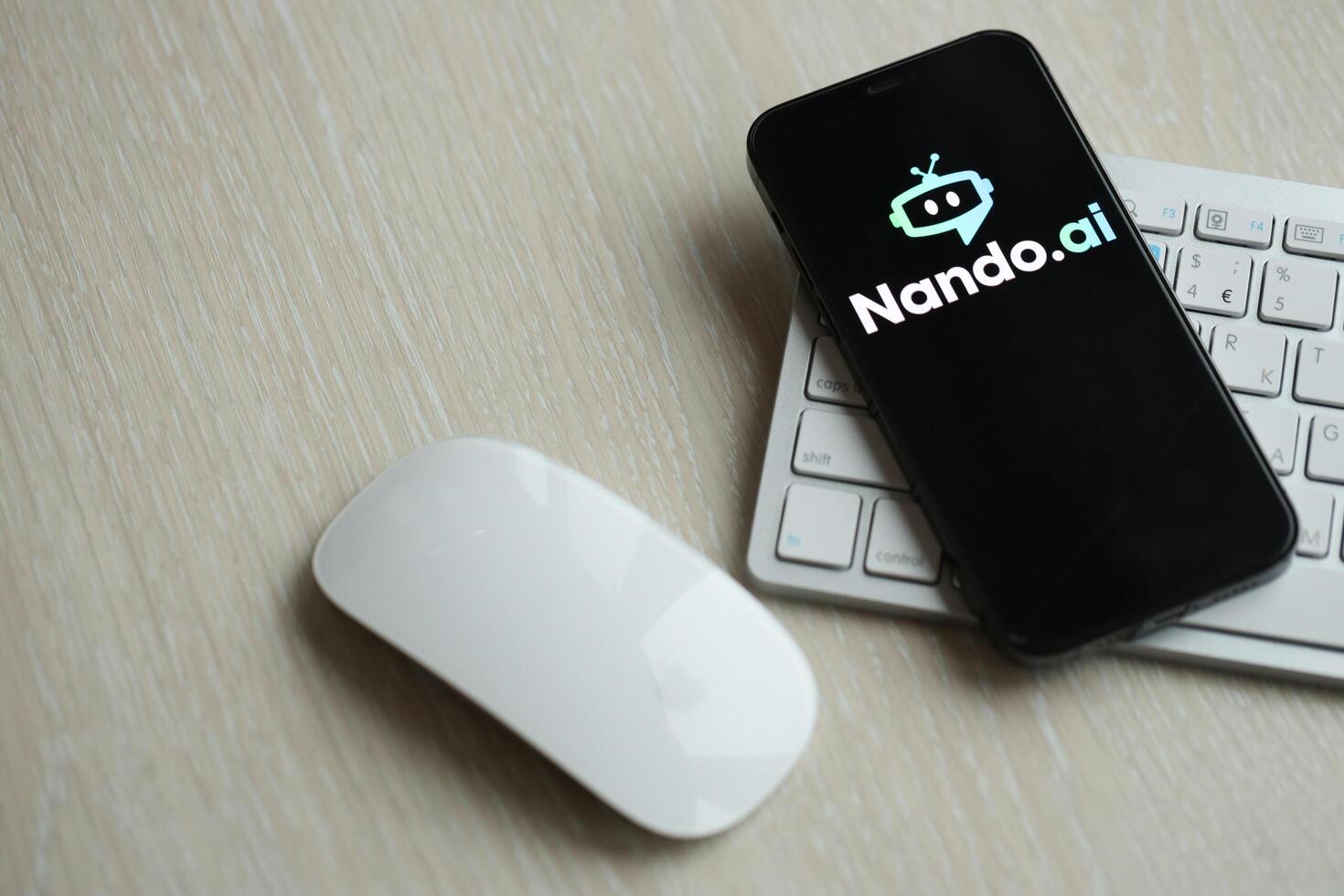 KYIV, UKRAINE - MARCH 17, 2024 NandoAI logo on iPhone display screen with apple keyboard and mouse on table photo