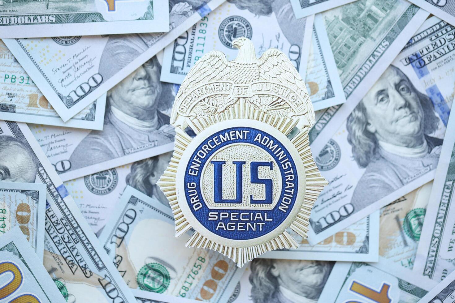 KYIV, UKRAINE - MARCH 9, 2024 US DEA Special Agent badge on many US hundred dollar bills photo