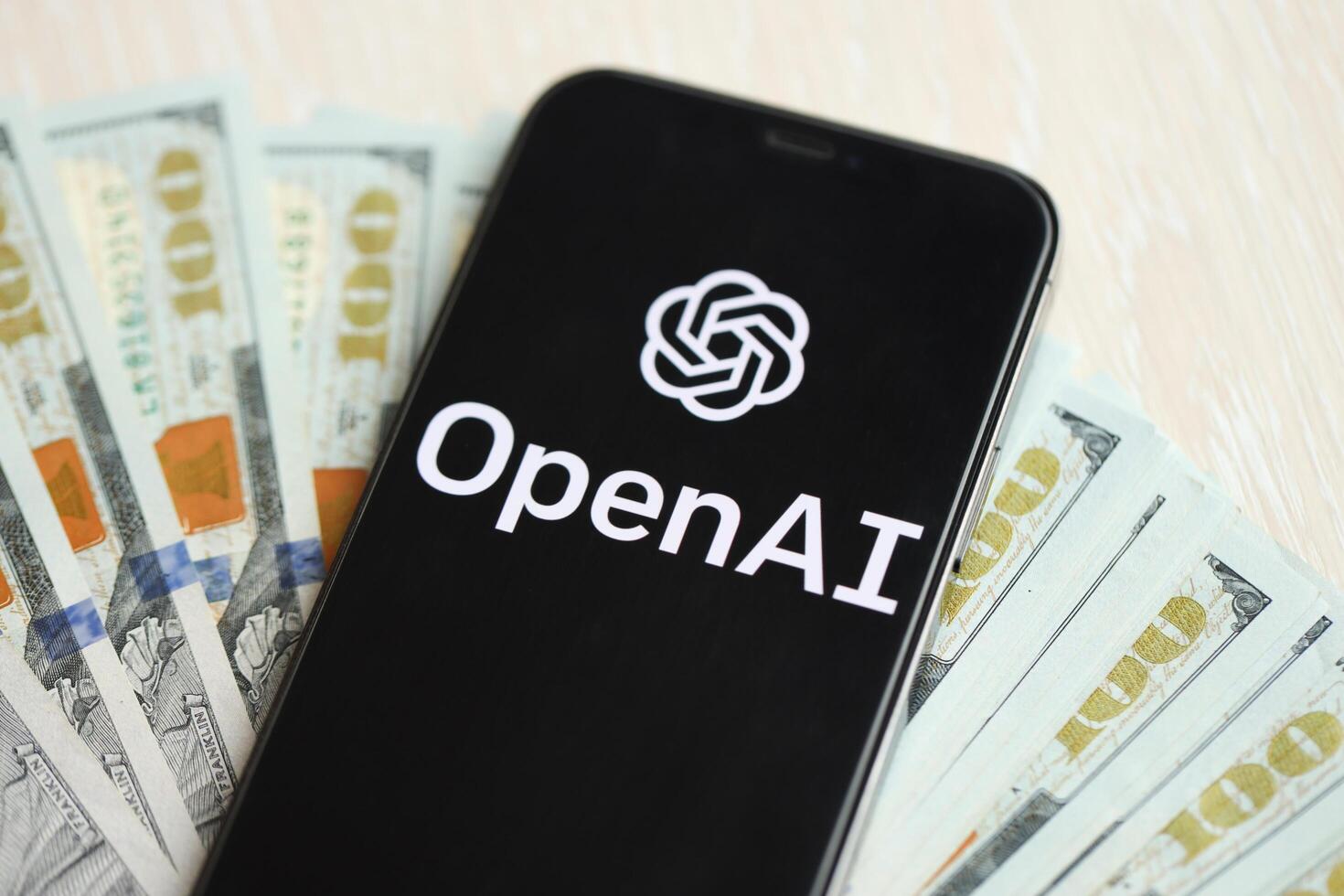 KYIV, UKRAINE - MARCH 17, 2024 OpenAI logo on iPhone display screen with many hundred dollar bills photo