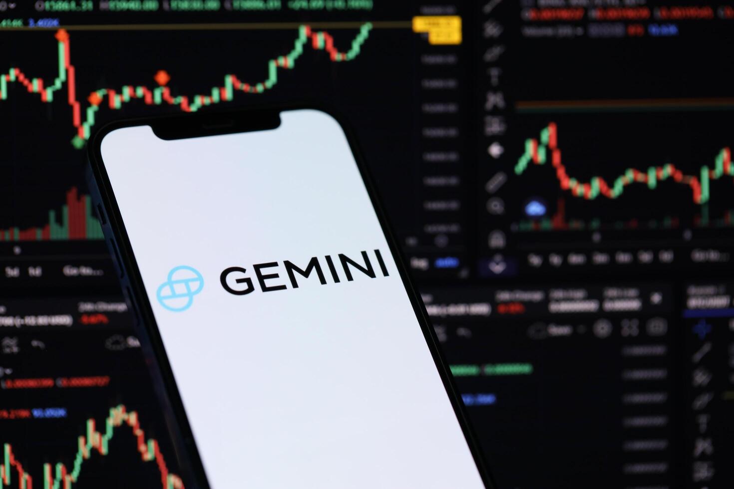 KYIV, UKRAINE - MARCH 15, 2024 Gemini logo on iPhone display screen and crypto currency value charts photo