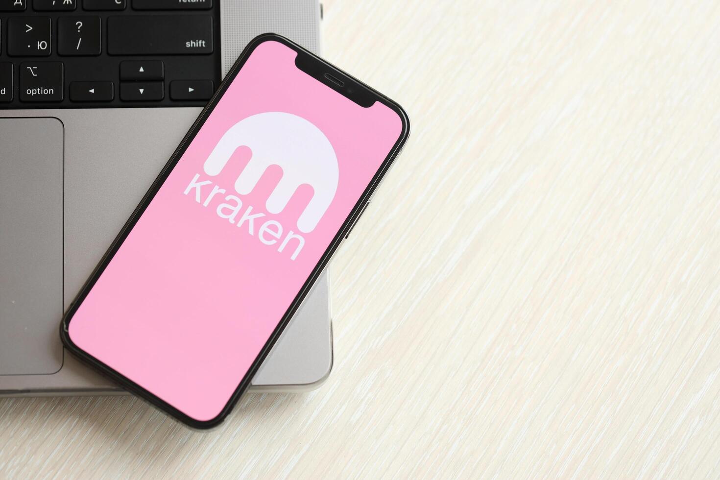 KYIV, UKRAINE - MARCH 15, 2024 Kraken logo on iPhone display screen on MacBook panel photo