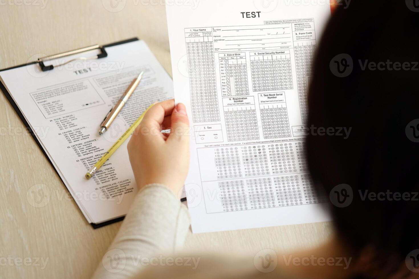Female student hands testing in exercise and hold exam paper sheet with pencil at school test room photo