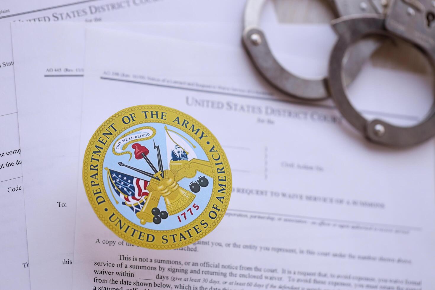 KYIV, UKRAINE - MARCH 9, 2024 US Department of Army seal with handcuffs on many US District Court warrants and complaints photo