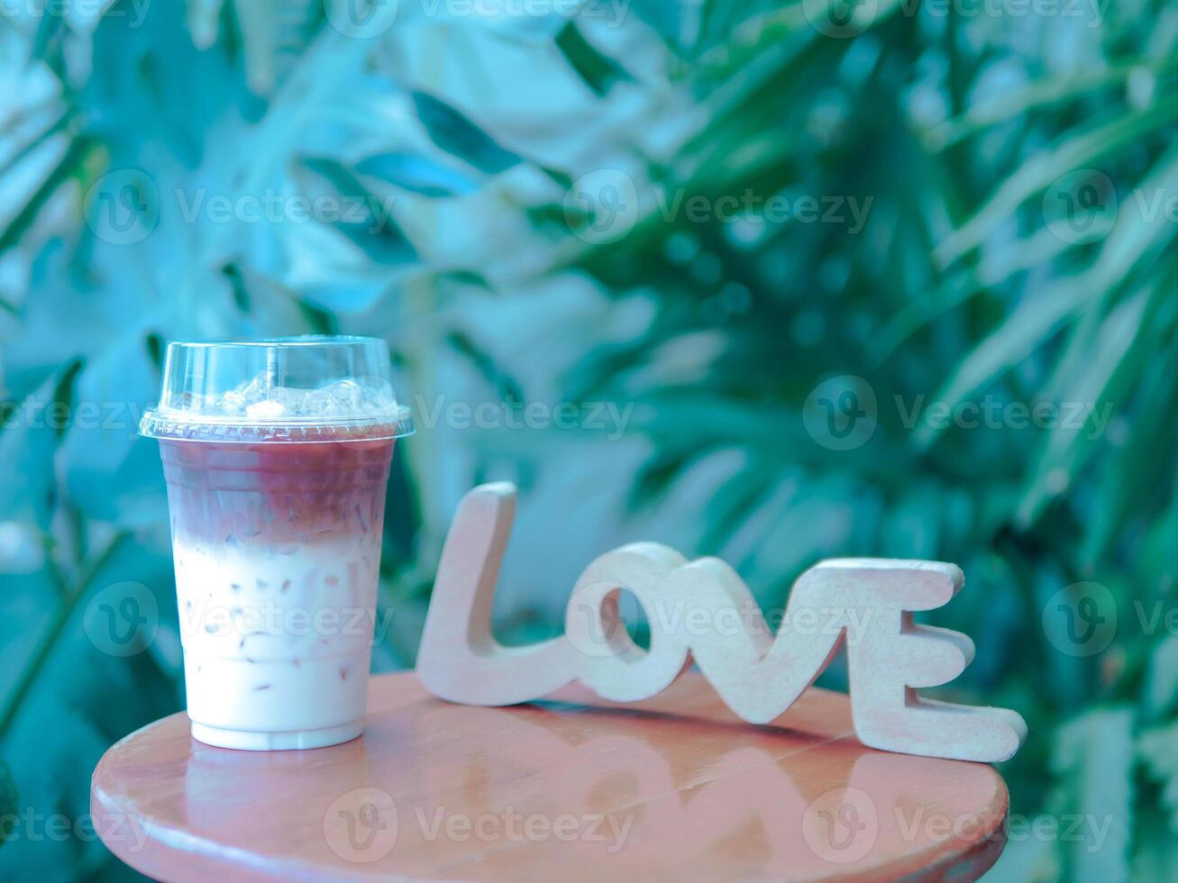 Iced coffee latte drink with wooden block word love on wooden table. photo
