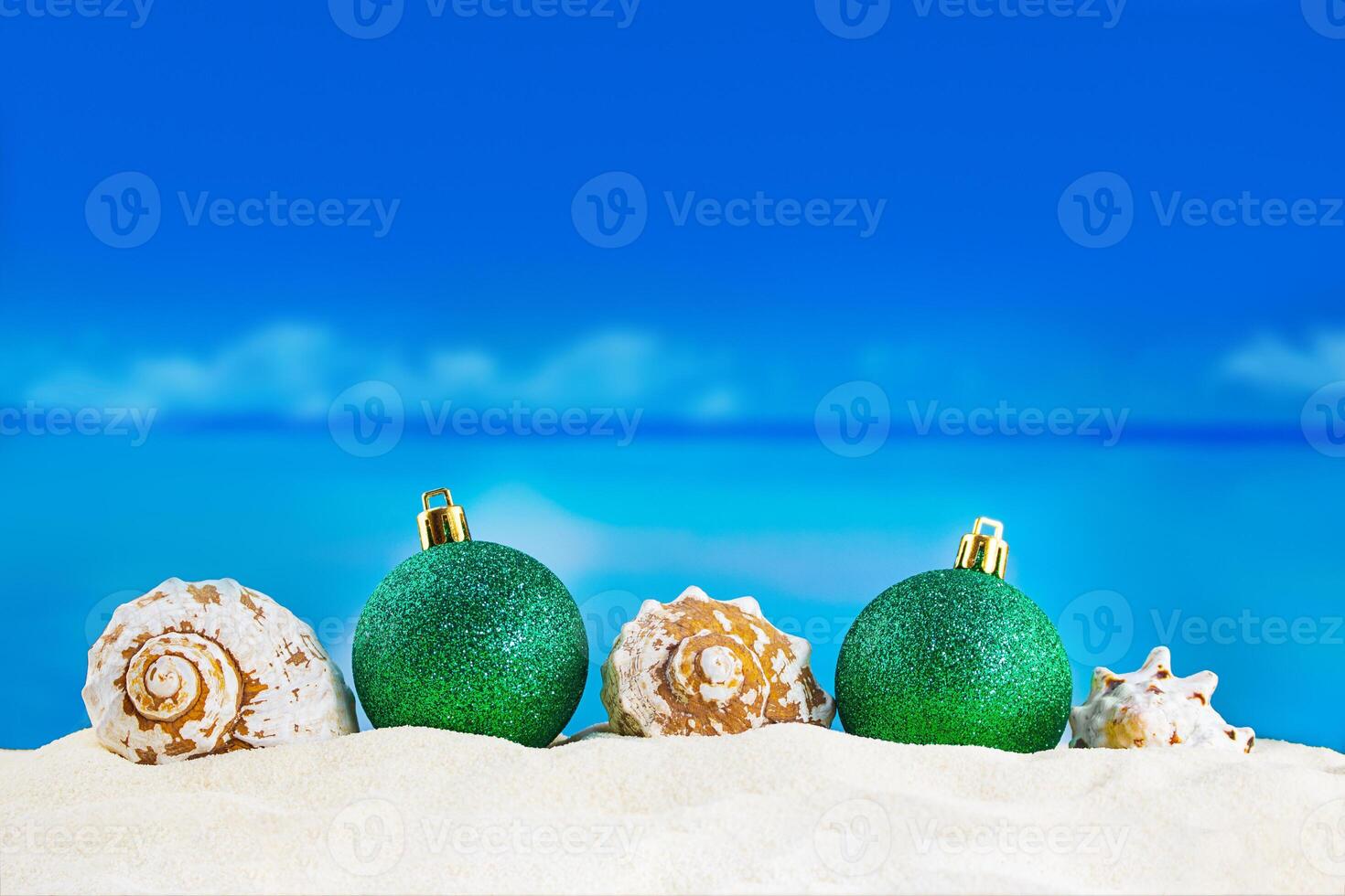 Shiny green balls with seashells on sand of beach. Christmas, New Year. Copy spaceShiny green balls with seashells on sand of beach. Christmas, New Year. Copy space photo