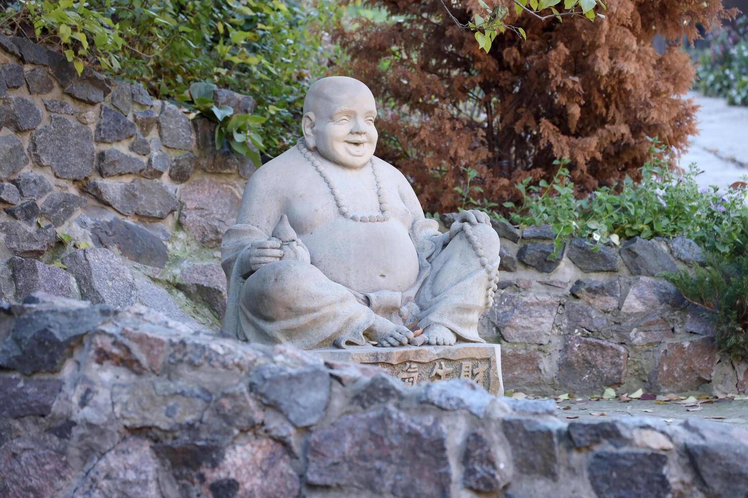 Cherkasy, UKRAINE - OCTOBER 20, 2021 Joyful Buddah concrete grey statue close to White Lotus buddhist temple photo