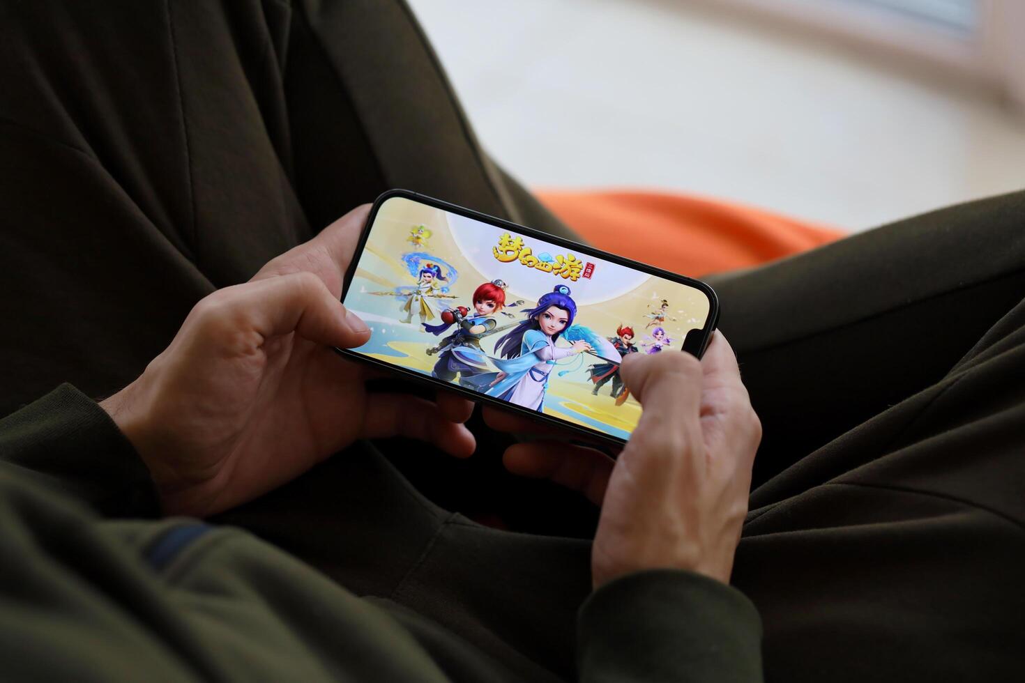 Fantasy Westward Journey mobile iOS game on iPhone 15 smartphone screen in male hands during mobile gameplay photo