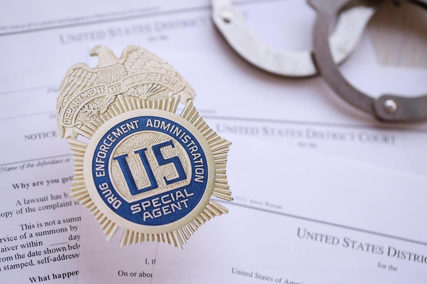 KYIV, UKRAINE - MARCH 9, 2024 US DEA Special Agent badge with handcuffs on many US District Court warrants and complaints photo