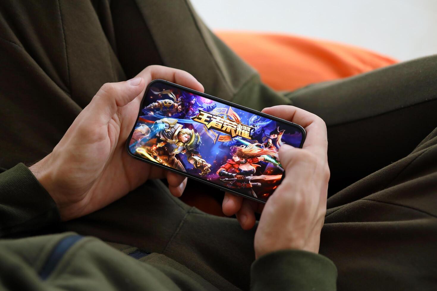 Honor of Kings mobile iOS game on iPhone 15 smartphone screen in male hands during mobile gameplay photo