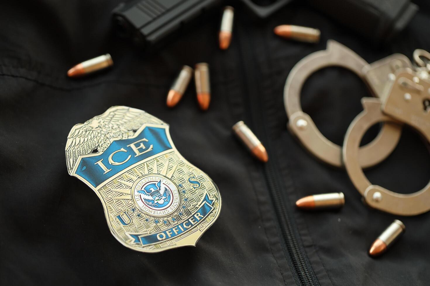 KYIV, UKRAINE - MARCH 9, 2024 US ICE Officer badge on black jacket uniform with gun, bullets and handcuffs photo