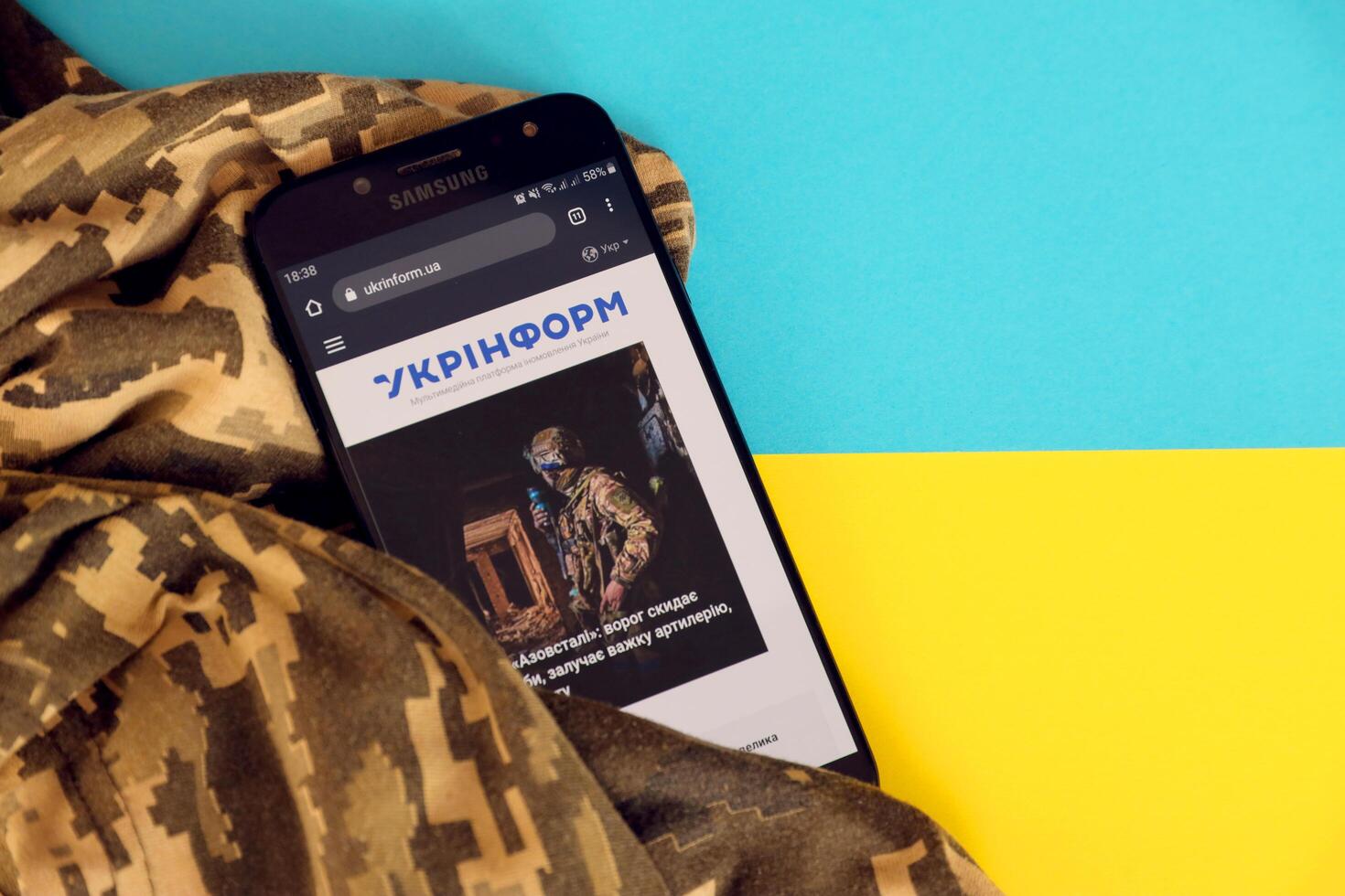 KYIV, UKRAINE - 4 MAY, 2023 Ukrinform ukrainian news portal on smartphone screen with ukrainian flag and camouflage fabric photo