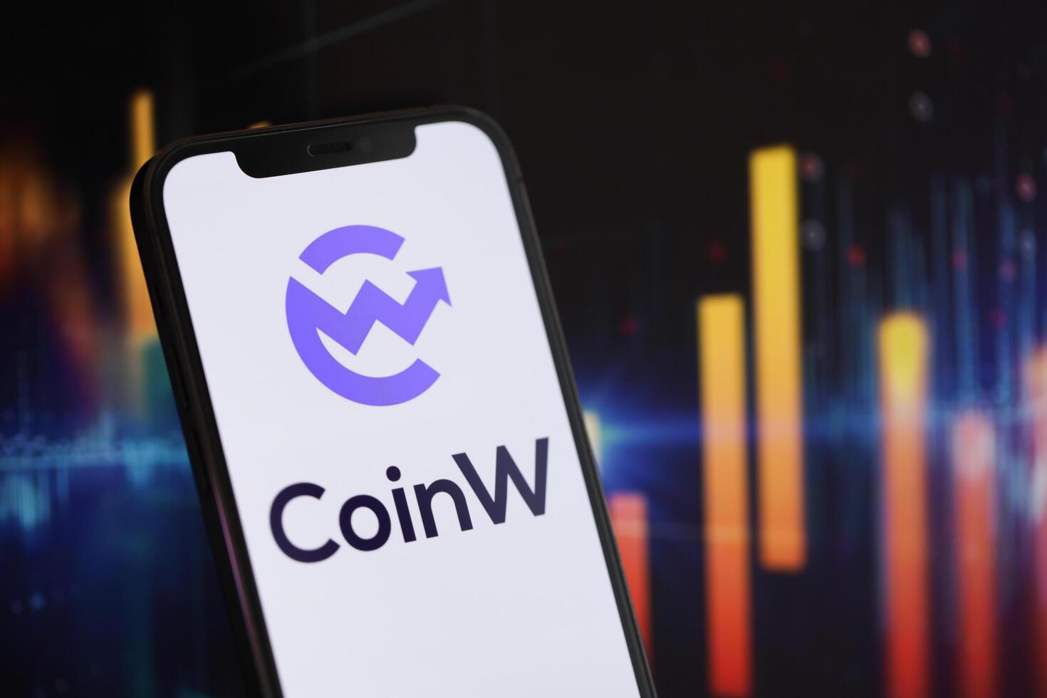 KYIV, UKRAINE - MARCH 15, 2024 CoinW logo on iPhone display screen and crypto currency value charts photo