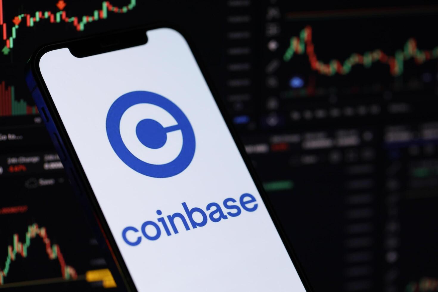 KYIV, UKRAINE - MARCH 15, 2024 Coinbase logo on iPhone display screen and crypto currency value charts photo