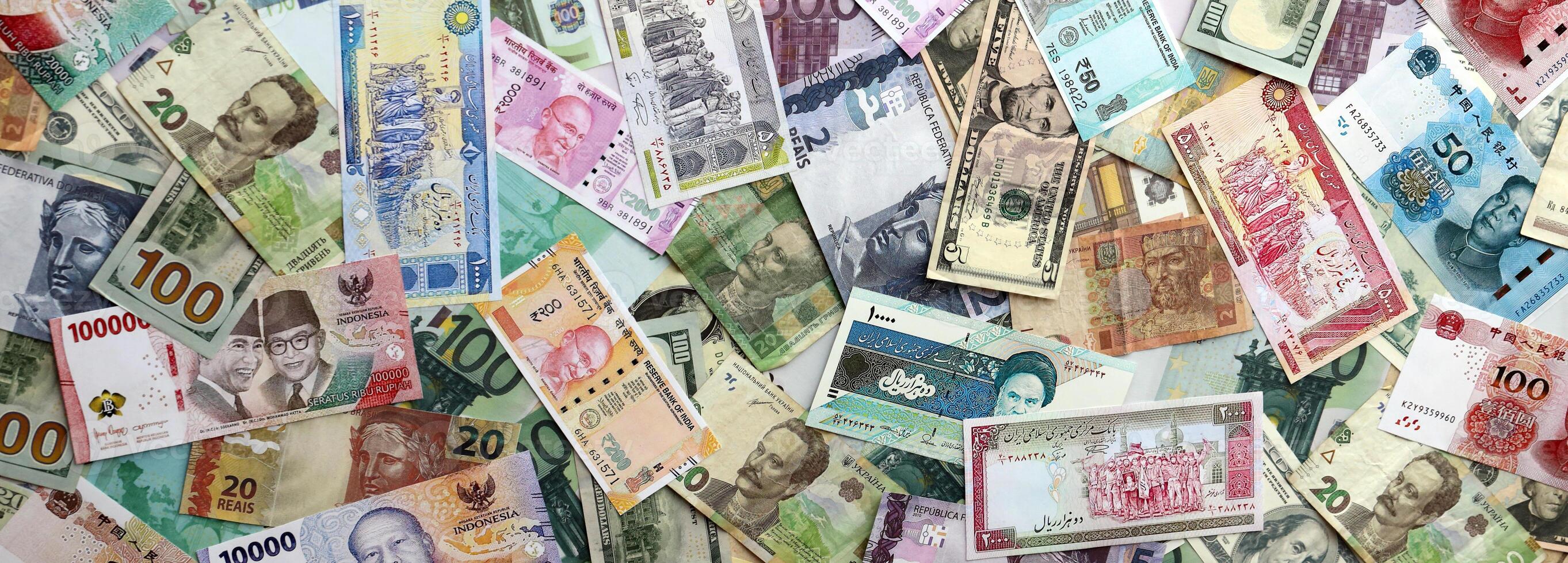 Many banknotes of different currency. Background of big amount of random money bills photo